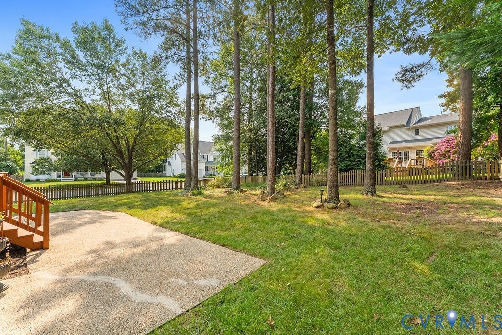5316 Lemoore Drive, Glen Allen, VA 23059 Expansive backyard featuring a concrete patio, wood deck with railings, lush green lawn, a wood picket fence, and mature trees