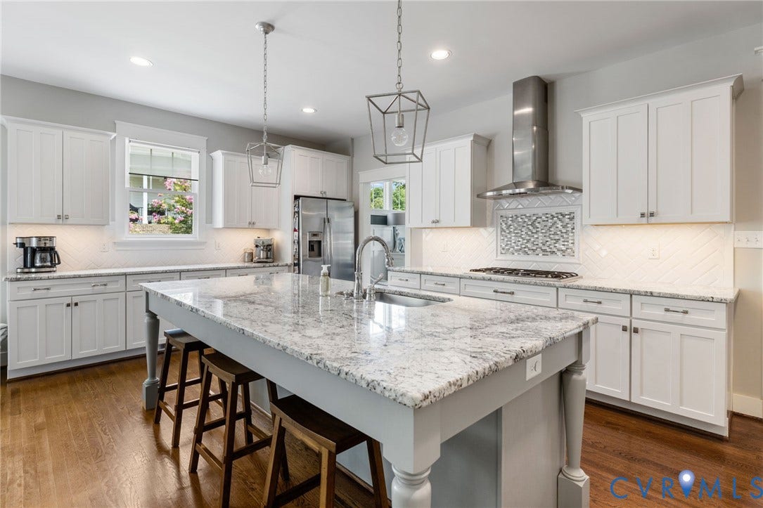 15918 Drumone Road, Hallsley, Midlothian, VA 23112 Spacious kitchen featuring an expansive central island with a built-in sink, white shaker-style cabinetry, stainless steel appliances, and wood-finish flooring