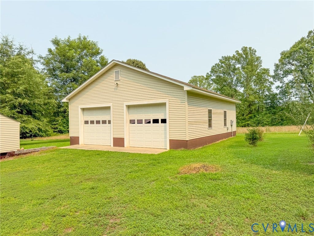 6688 Old Buckingham Road, Powhatan, VA 23139 Detached two-car garage featuring two individual bay doors with window inserts, light-toned horizontal siding, and a contrasting dark base