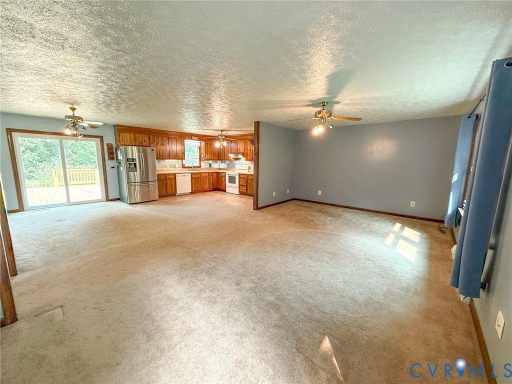 6688 Old Buckingham Road, Powhatan, VA 23139 Open-concept living area featuring a kitchen with wood cabinetry, stainless steel refrigerator, and white appliances