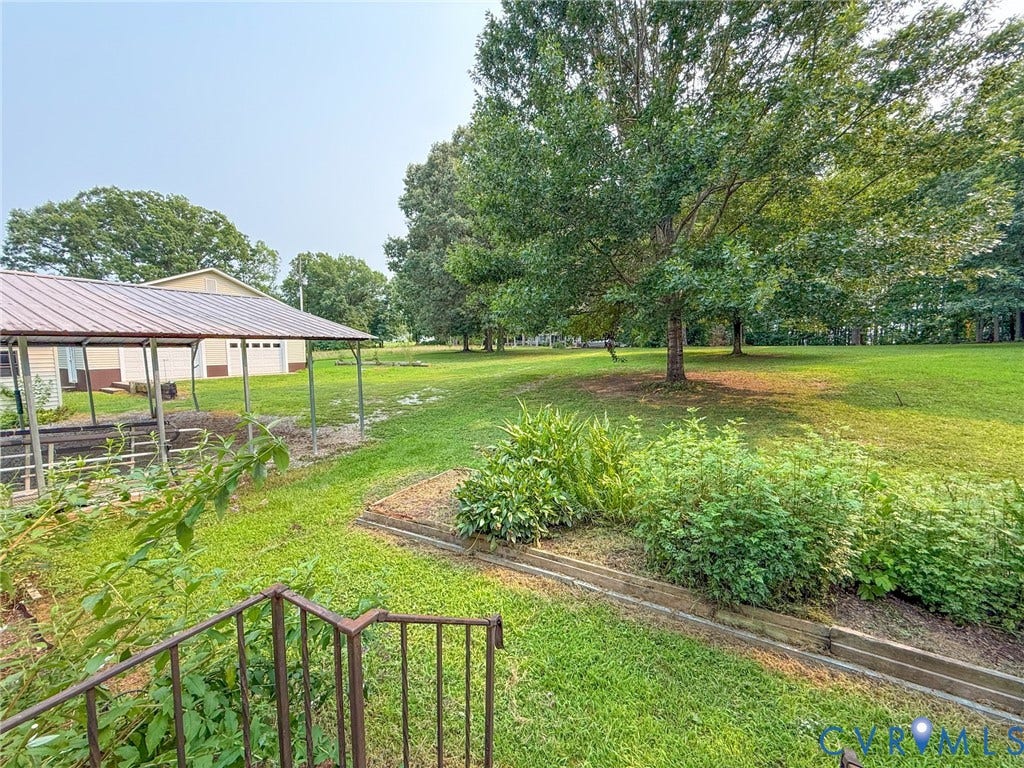 6688 Old Buckingham Road, Powhatan, VA 23139 Expansive outdoor space featuring a covered structure with a metal roof, a detached two-car garage, mature trees, and landscaping elements