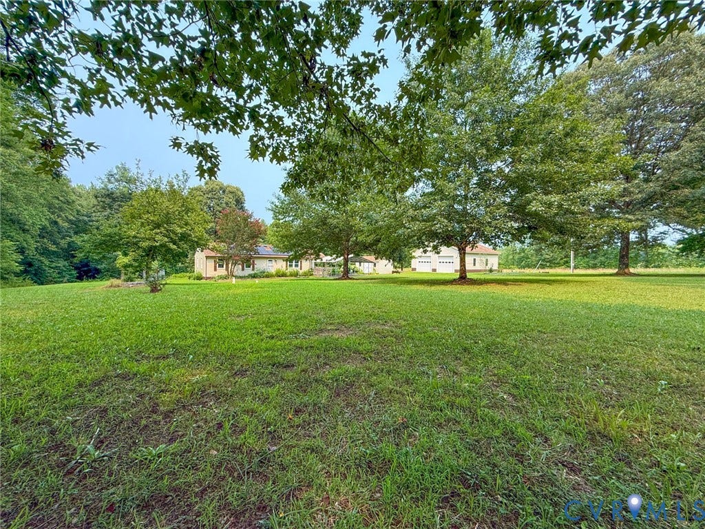 6688 Old Buckingham Road, Powhatan, VA 23139 Expansive green lawn with mature trees and a light-colored single-story residence in the background