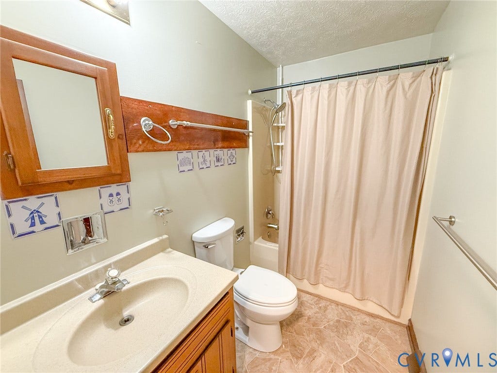 6688 Old Buckingham Road, Powhatan, VA 23139 Bathroom featuring a single vanity with an integrated sink, a built-in medicine cabinet with a mirror, a toilet, a shower-tub combination, and patterned floor tiling