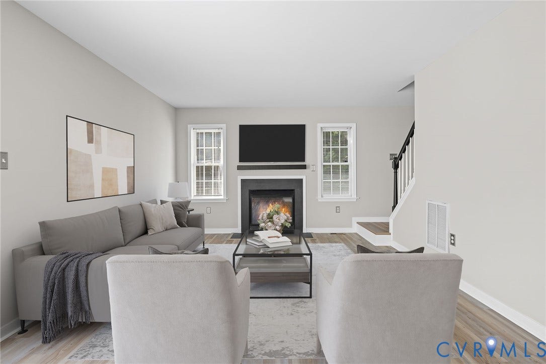 5025 Alberta Mews, Chesterfield, VA 23832 Living area featuring a fireplace with a black surround and mantel, LVP flooring, light-toned walls, and a staircase with a white and black banister. Virtually staged concept