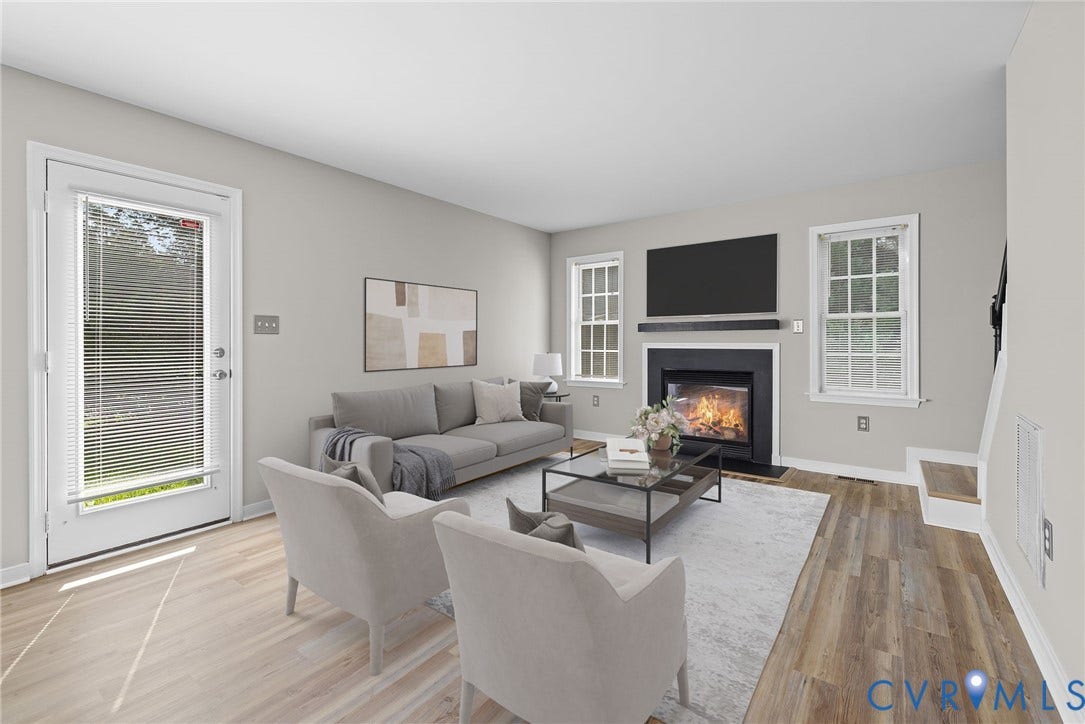 5025 Alberta Mews, Chesterfield, VA 23832 Living area featuring a black gas fireplace with a wood mantel, LVP flooring, light gray wall tones, and multiple windows. Virtually staged concept
