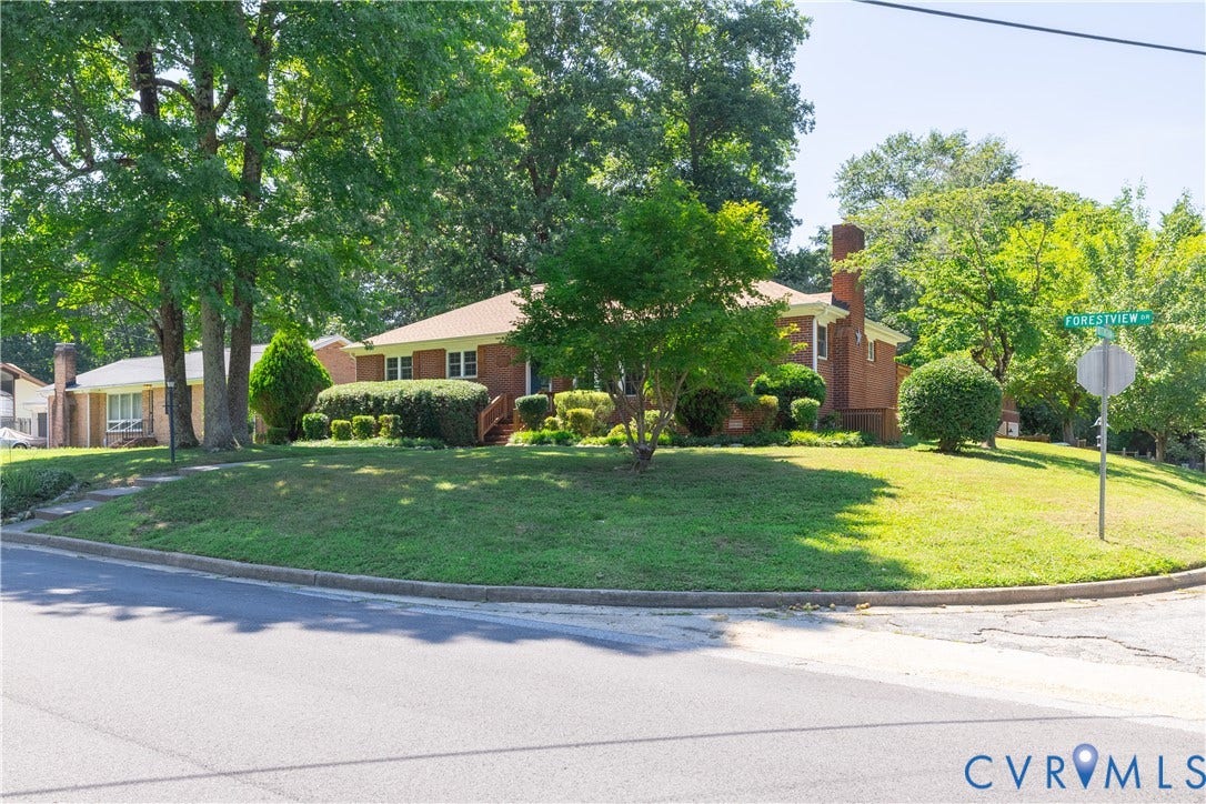 704 Forestview Drive, Colonial Heights, VA 23834 Brick exterior residence featuring a corner lot, mature trees, established landscaping, and a sloped lawn