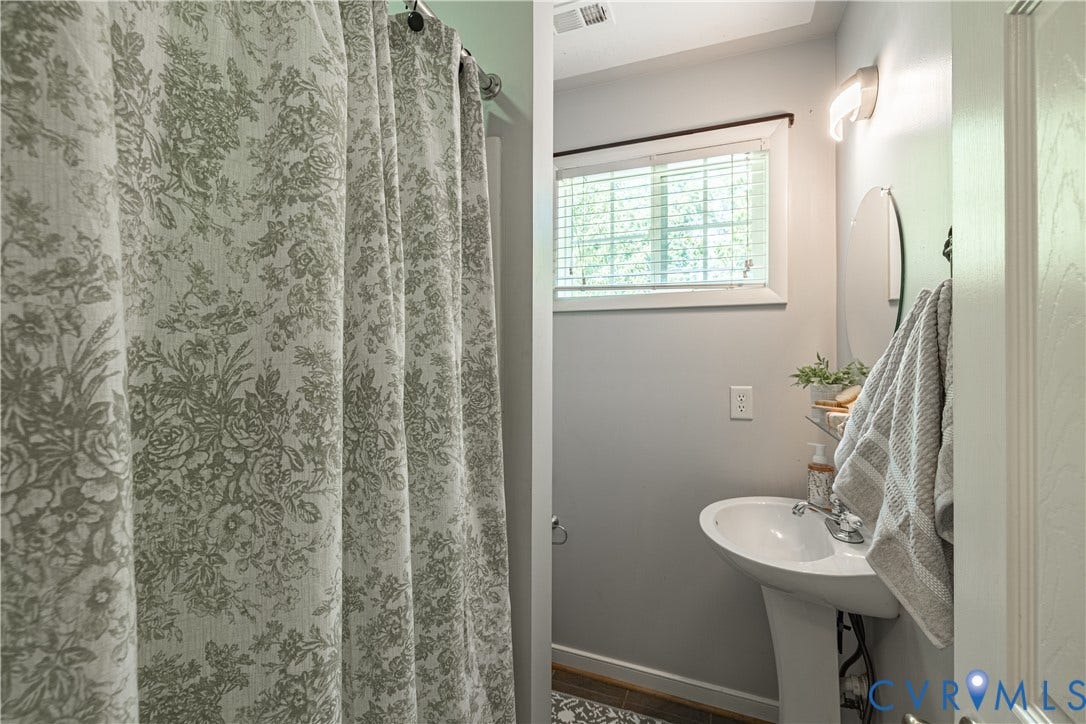 704 Forestview Drive, Colonial Heights, VA 23834 Pedestal sink with an oval mirror, wall-mounted light fixture, and a window with blinds