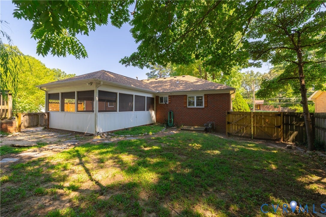 704 Forestview Drive, Colonial Heights, VA 23834 Expansive backyard featuring a screened porch, mature perimeter trees, brick exterior, and a wooden privacy fence with double gates