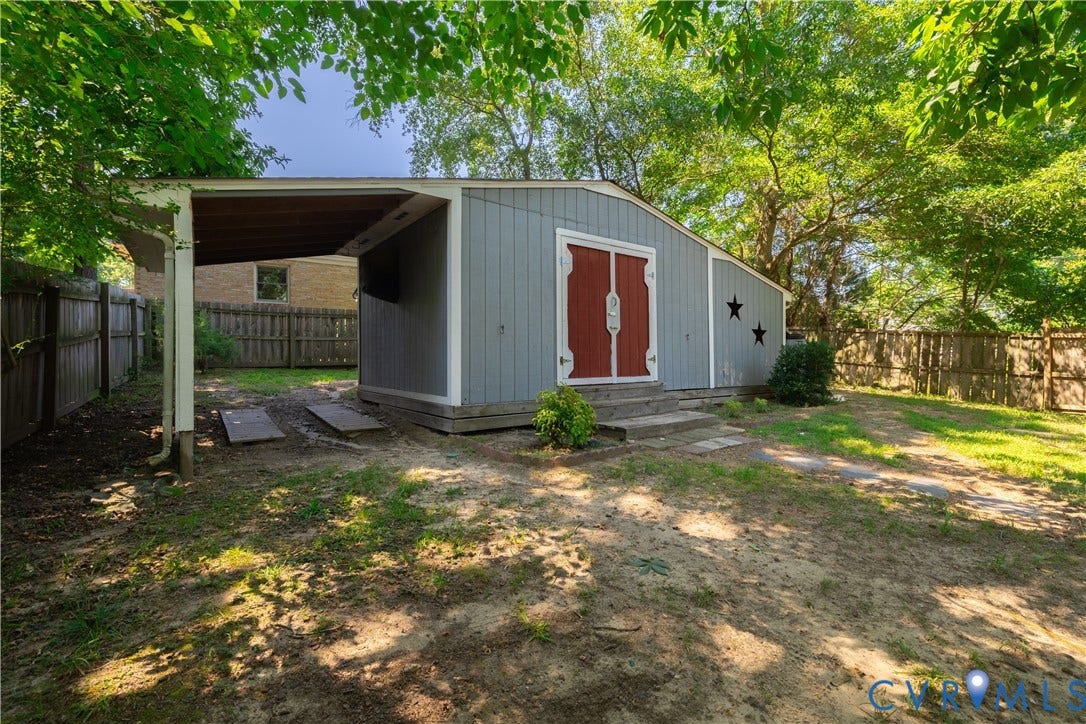 704 Forestview Drive, Colonial Heights, VA 23834 Detached shed with light blue siding and red double doors, featuring a covered side extension and a surrounding wooden fence