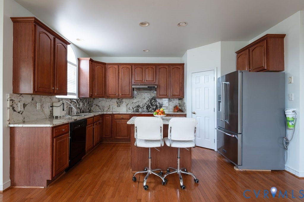 4924 Sadler Glen Ct, Sadler Glen, Glen Allen, VA 23060 Kitchen featuring wood-finish flooring, an island with seating, a stainless steel refrigerator, and dark wood cabinetry