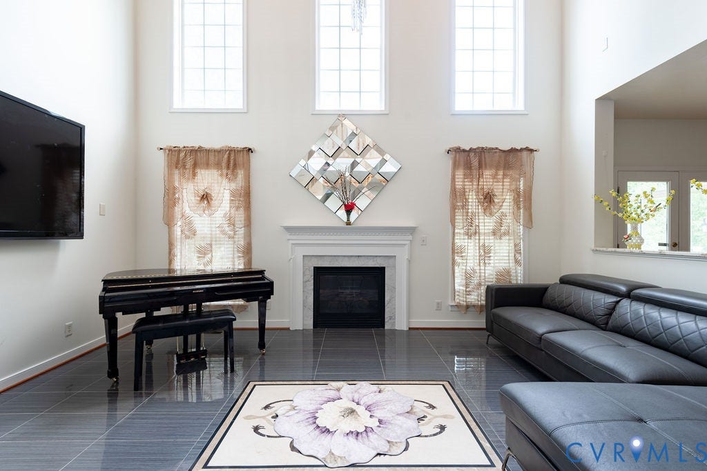 4924 Sadler Glen Ct, Sadler Glen, Glen Allen, VA 23060 Spacious living area featuring high ceilings, large windows, a fireplace with a stone surround and white mantel, and dark tile flooring