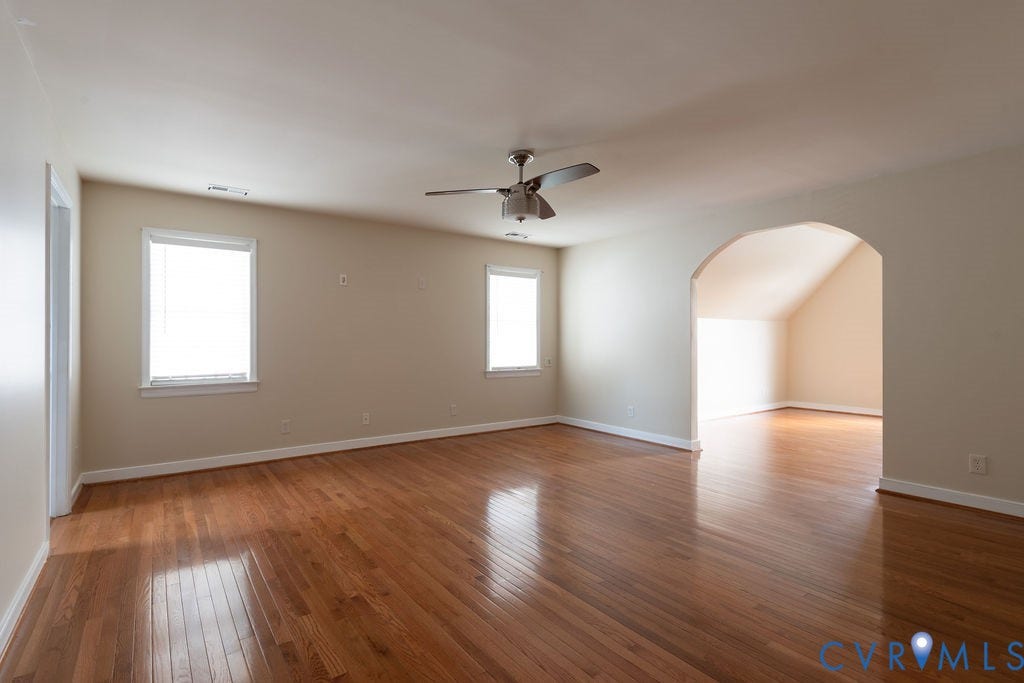 4924 Sadler Glen Ct, Sadler Glen, Glen Allen, VA 23060 Spacious room featuring wood-finish flooring, multiple windows, a ceiling fan, and an arched entryway to an additional area