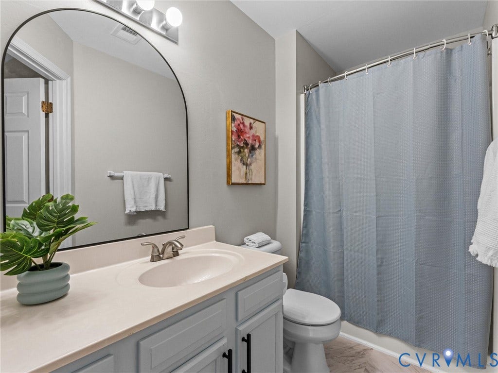 10100 Robin Lee Lane, Laurel Lakes, Glen Allen, VA 23060 Bathroom featuring a vanity with a light countertop and integrated sink, a rectangular mirror with an arched top, a wall-mounted light fixture, and a shower-tub combination with a shower curtain rod