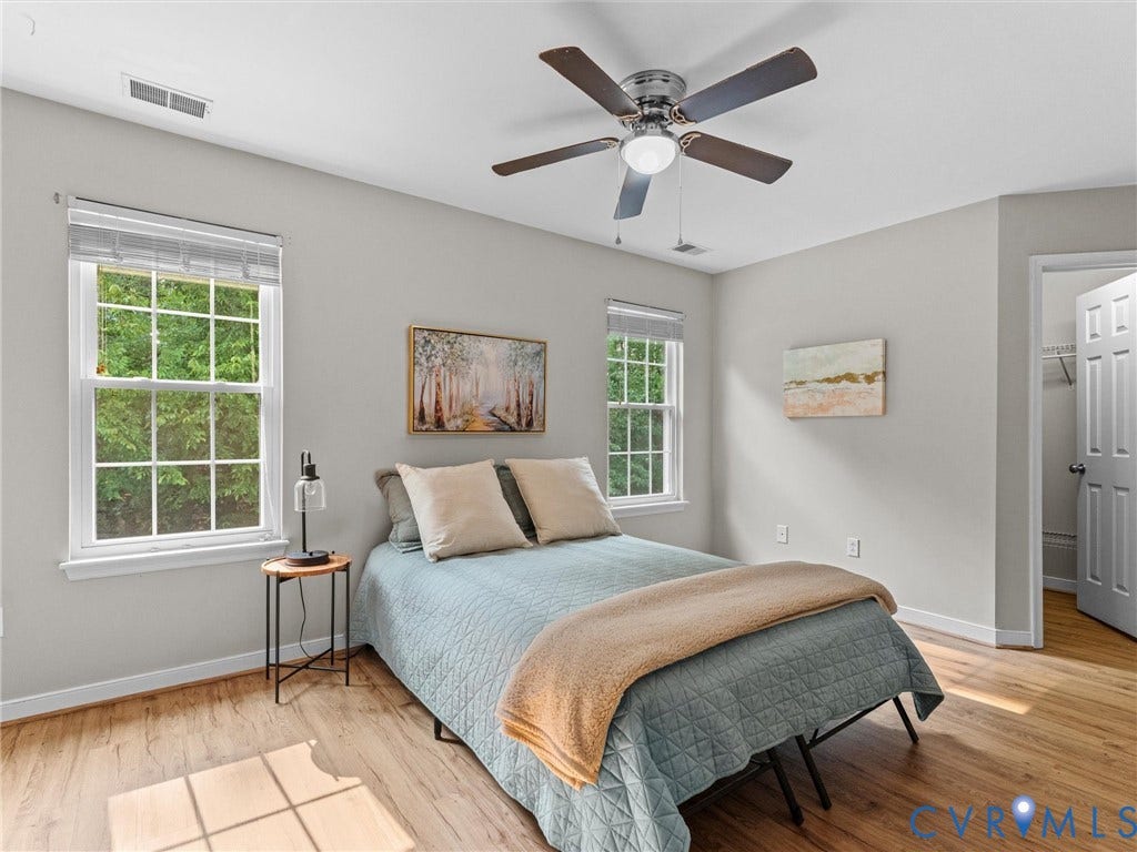 10100 Robin Lee Lane, Laurel Lakes, Glen Allen, VA 23060 Light-filled room featuring two large windows, wood-finish flooring, a ceiling fan with integrated lighting, and a white paneled door