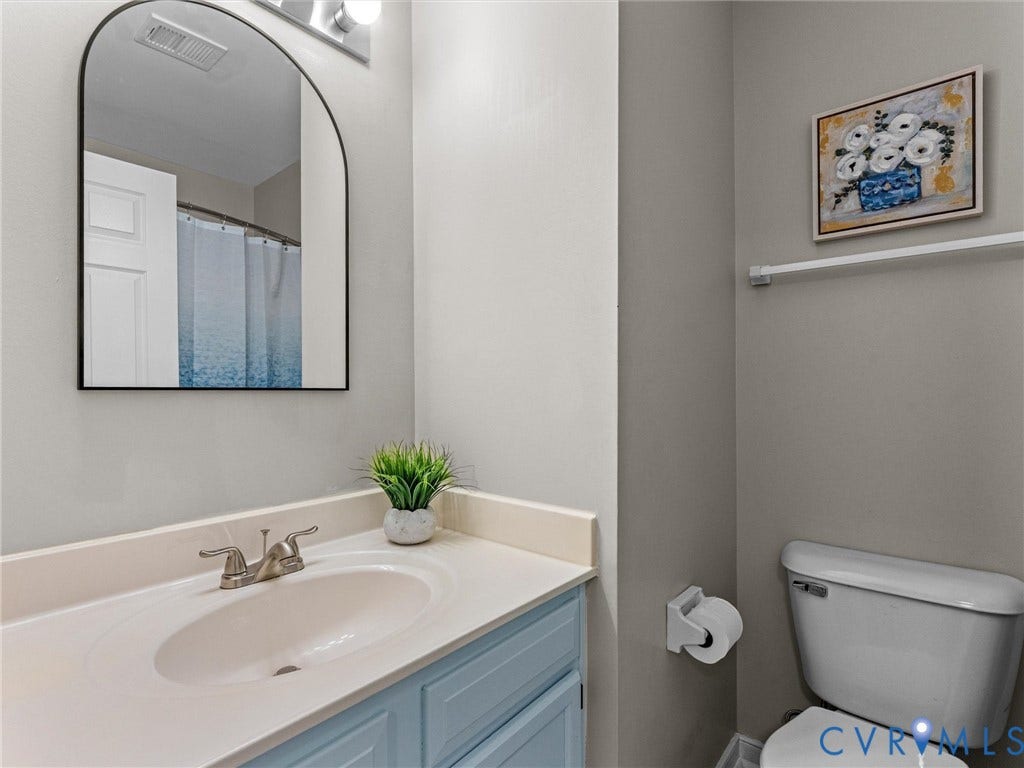 10100 Robin Lee Lane, Laurel Lakes, Glen Allen, VA 23060 Bathroom featuring a light blue vanity with a white countertop and an integrated sink, brushed nickel faucet, and an arched black-framed mirror