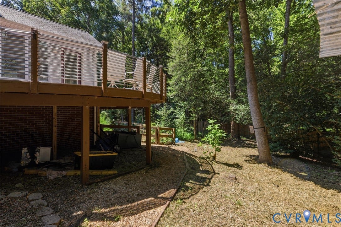 5215 Lippingham Lane, Stoney Glen West, Chester, VA 23831 Elevated wood-tone deck with white slatted railing, brick foundation, and natural tree coverage