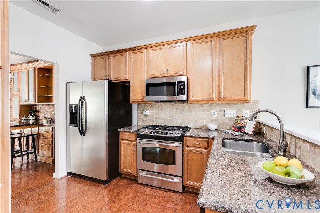 8004 Creekside Village Drive, Creekside Village, Mechanicsville, VA 23111 Kitchen featuring wood-finish flooring, light wood cabinetry, stainless steel appliances, speckled countertops, and a tile backsplash
