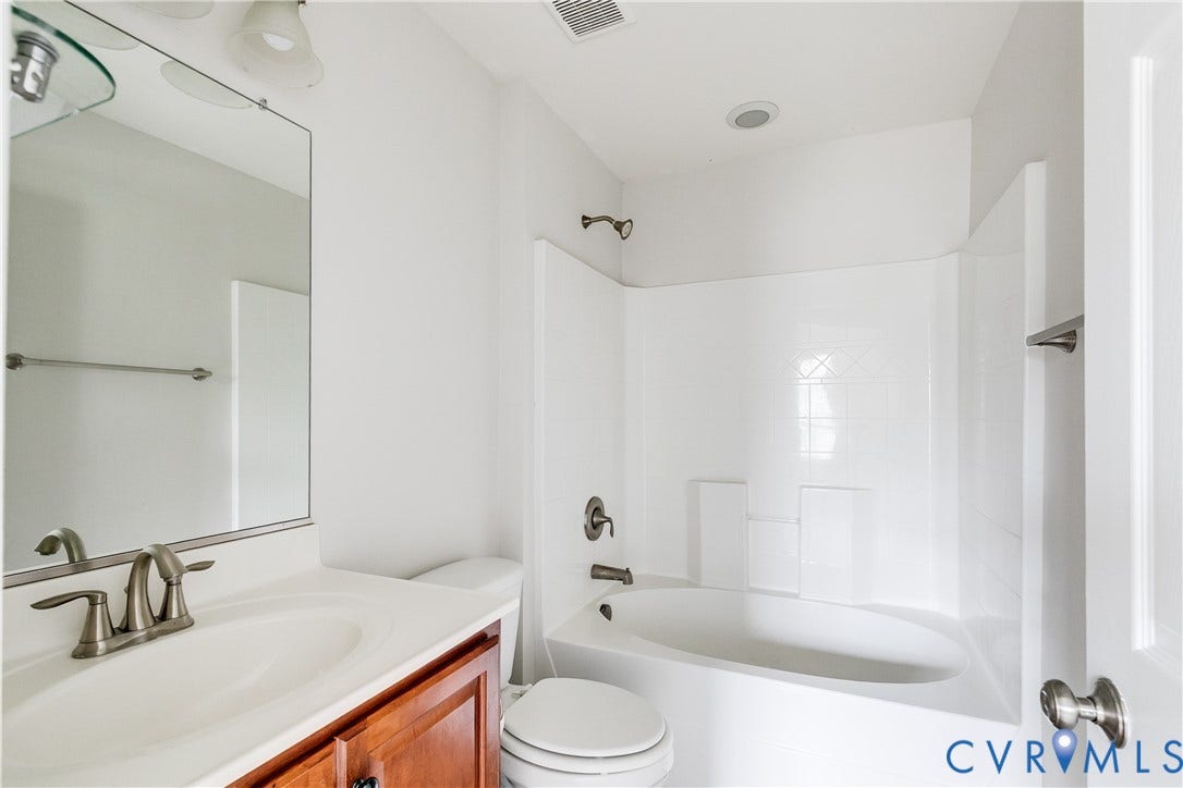 8004 Creekside Village Drive, Creekside Village, Mechanicsville, VA 23111 Bathroom featuring a white ceramic bathtub with shower, white tile surround, and brushed nickel fixtures