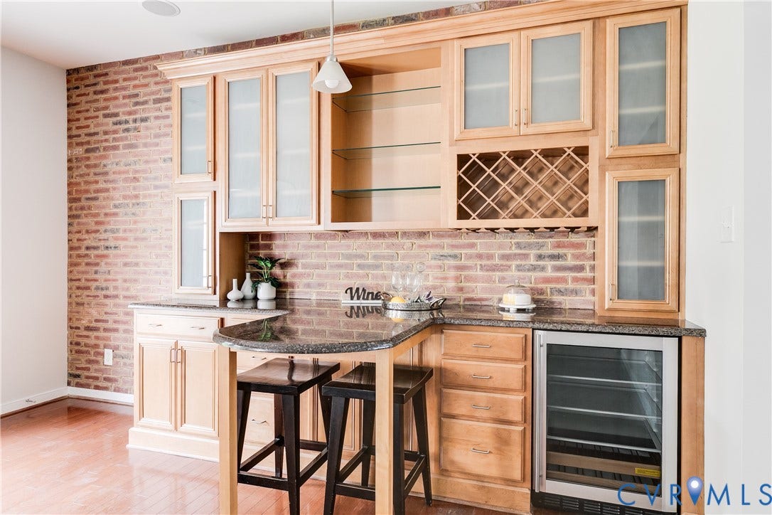 8004 Creekside Village Drive, Creekside Village, Mechanicsville, VA 23111 Built-in wet bar featuring light wood cabinetry, brick-patterned wall, integrated wine rack, recessed shelving, and a beverage cooler