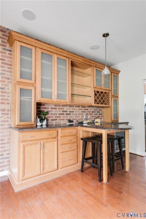 8004 Creekside Village Drive, Creekside Village, Mechanicsville, VA 23111 Built-in wet bar featuring wood-finish cabinetry, frosted glass cabinet doors, stone-finish countertops, and an integrated wine rack