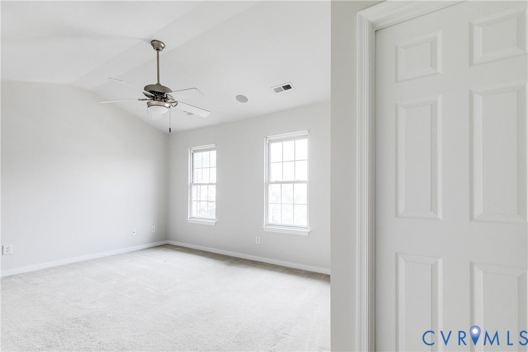 8004 Creekside Village Drive, Creekside Village, Mechanicsville, VA 23111 Spacious room featuring vaulted ceilings, a ceiling fan with integrated lighting, two double-hung windows, light-colored carpeting, and a six-panel interior door