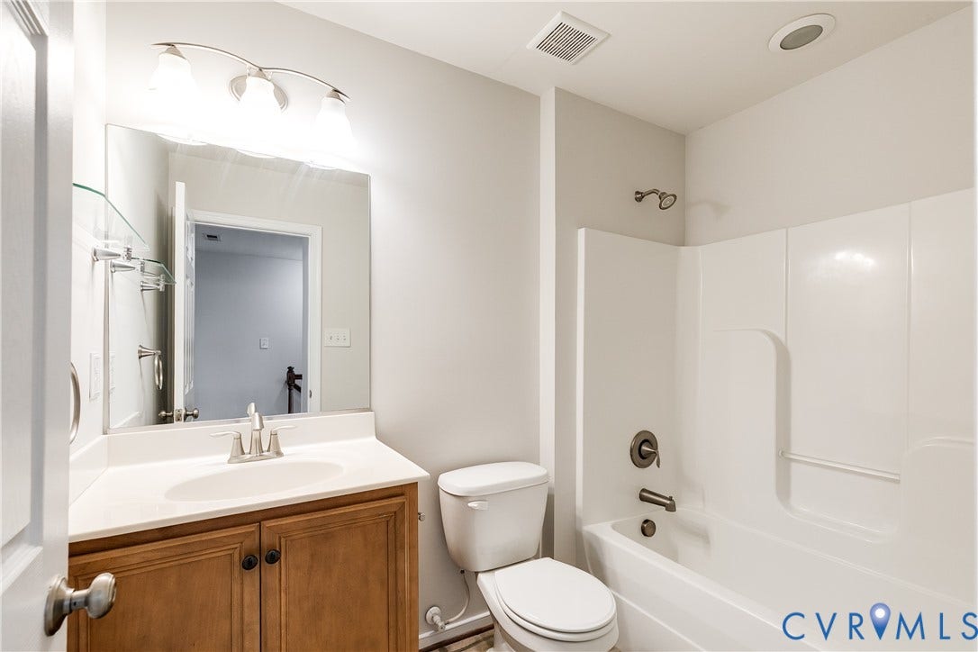 8004 Creekside Village Drive, Creekside Village, Mechanicsville, VA 23111 Bathroom featuring a white bathtub/shower combination, a vanity with wood-finish cabinetry, a white countertop, and an integrated sink