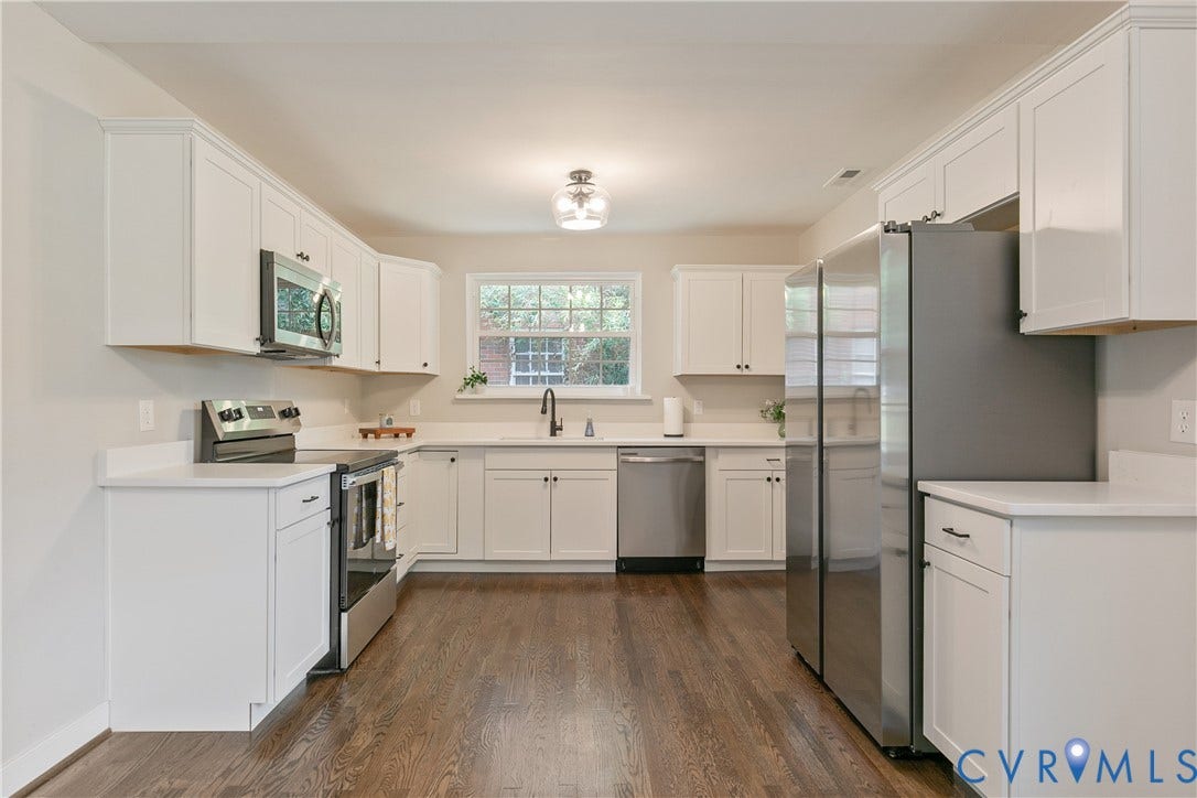 3512 Fendall Avenue, Edgewood, Richmond, VA 23222 Spacious kitchen featuring white shaker cabinetry, stainless steel appliances, a window over the sink, solid surface countertops, and wood-finish flooring