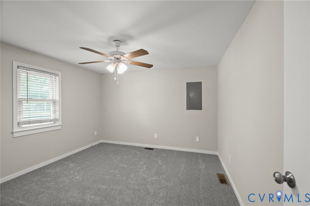 Carpeted interior room featuring a ceiling fan with light fixture, a single window with blinds, and light-toned walls