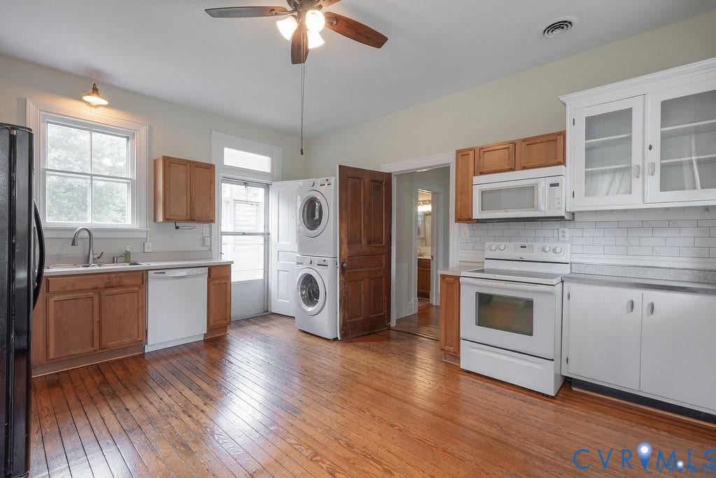 11300 Aspen Grove Drive, Glen Allen, VA 23059 Kitchen featuring wood-finish flooring, wood cabinetry, white appliances, subway tile backsplash, and a stacked washer and dryer unit