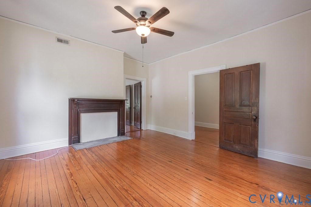 11300 Aspen Grove Drive, Glen Allen, VA 23059 Expansive room featuring rich wood-finish flooring, a detailed dark wood fireplace surround, white baseboards, and a ceiling fan with integrated lighting