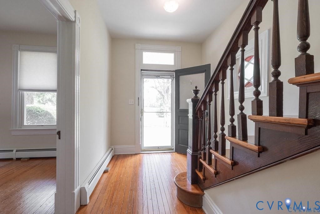11300 Aspen Grove Drive, Glen Allen, VA 23059 Foyer entry featuring wood-finish flooring, a traditional wooden staircase with detailed banisters, bright white trim, and a prominent front door with a transom window