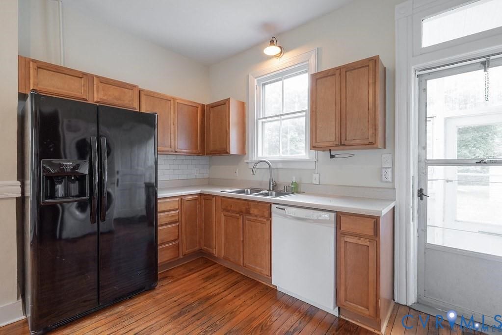 11300 Aspen Grove Drive, Glen Allen, VA 23059 Kitchen featuring wood-finish flooring, a black side-by-side refrigerator, light wood cabinetry, white subway tile backsplash, and a double basin sink
