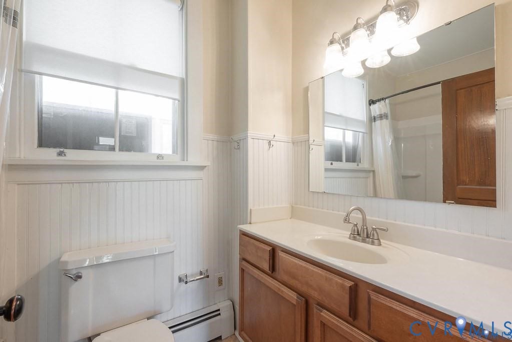 11300 Aspen Grove Drive, Glen Allen, VA 23059 Bathroom featuring a wood vanity with a white countertop and integrated sink, beadboard wainscoting, and a window with a roller shade