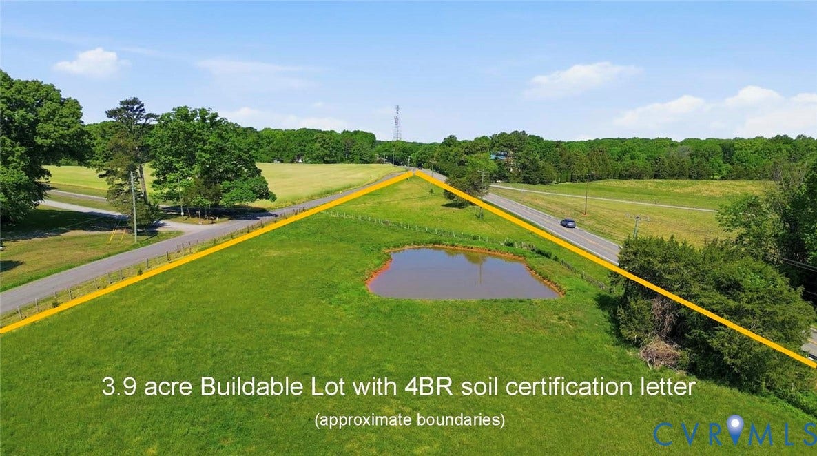 Expansive 3.9-acre lot with a visible pond, bordered by a road, and featuring mature trees