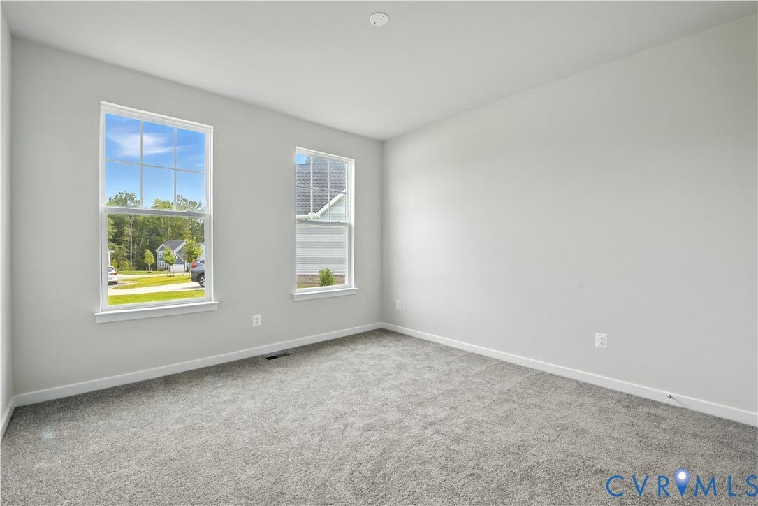 Bright interior space featuring two windows with white trim, light gray walls, and gray carpet flooring