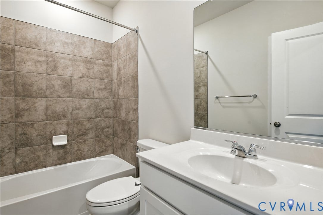 Bathroom featuring a white vanity with an integrated sink, chrome faucet, and a large wall-mounted mirror