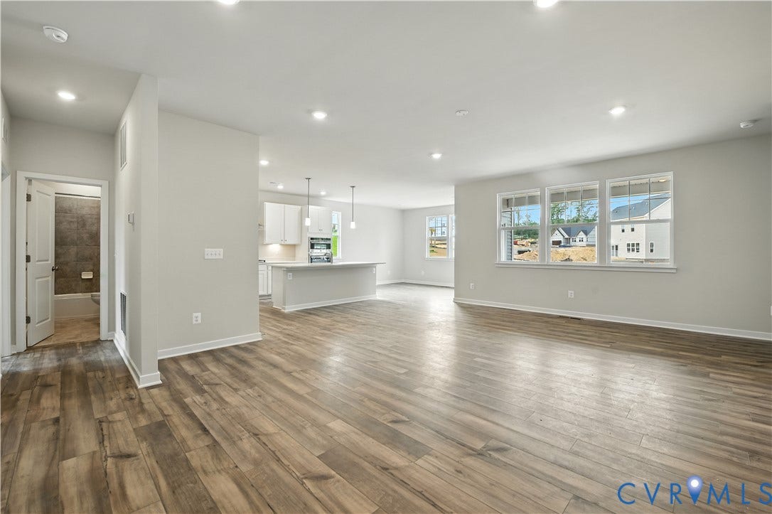 Spacious open concept living area featuring wood-finish flooring, recessed lighting, and multiple windows