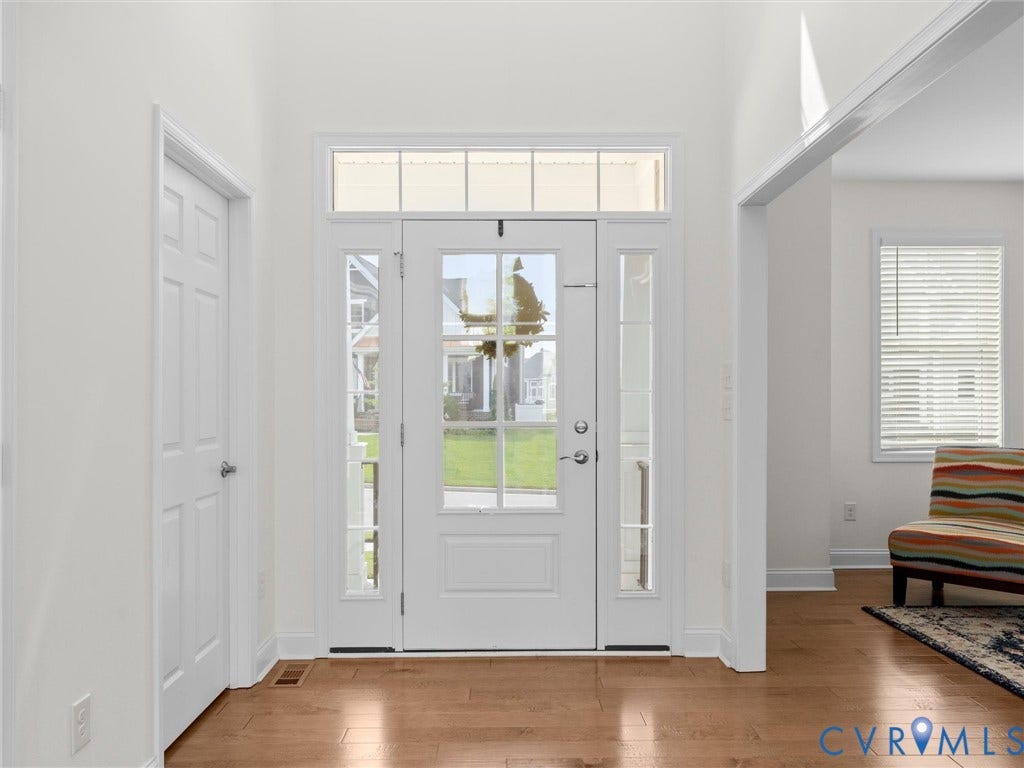 6642 Stonewolf Court, Moseley, VA 23120 Two-panel glass-inset entry door with transom window and sidelights, complemented by wood-finish flooring and white trim