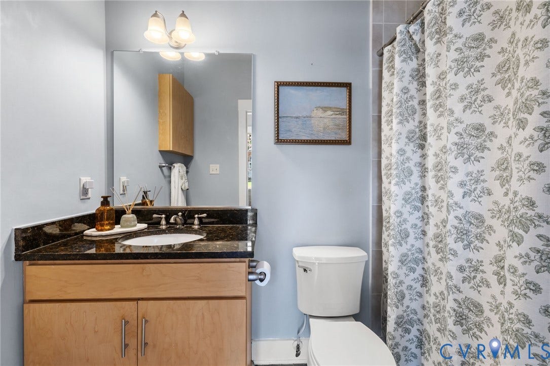2318 Herbert Hamlet Alley, #U4, Richmond, VA 23220 Full Hall Bath has ceramic tile floor, warm wood vanity with granite top and a convenient added wall cabinet (visible in the mirror reflection). Tub/shower has ceramic tile surround.