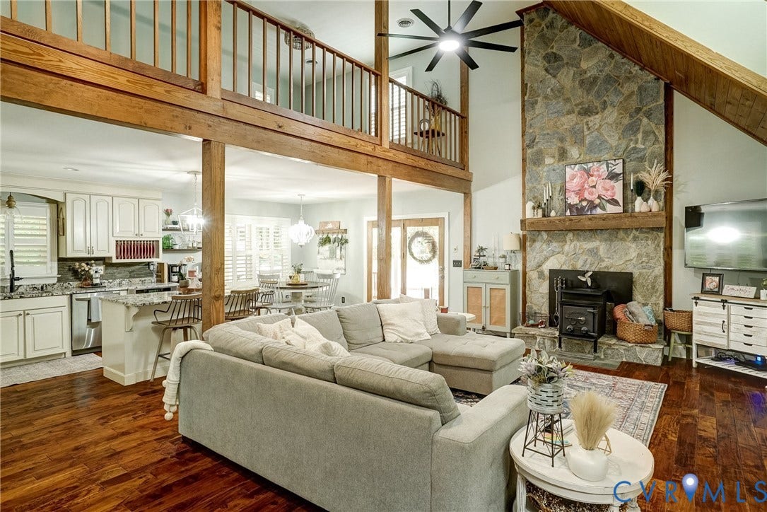 1174 Dorset Road, Powhatan, VA 23139 Two-story living area featuring a stone fireplace with wood-burning insert, vaulted ceiling, and exposed wood beams