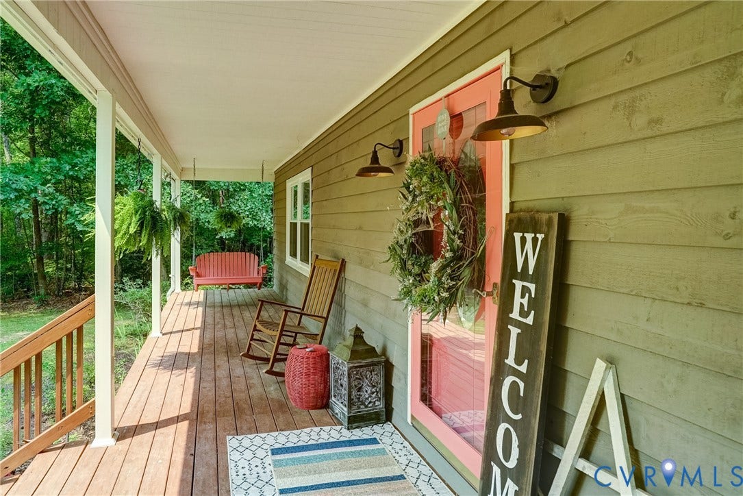 1174 Dorset Road, Powhatan, VA 23139 Expansive covered front porch with wood flooring, white support columns, and a light green siding exterior