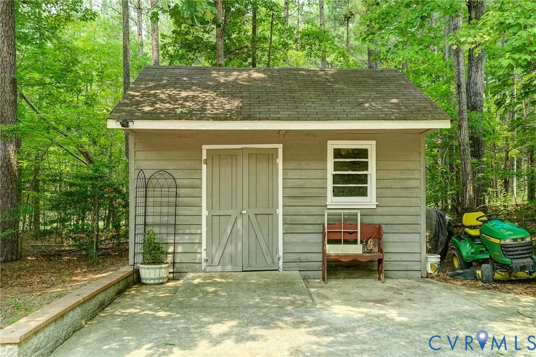1174 Dorset Road, Powhatan, VA 23139 Detached storage shed with horizontal siding and a shingled roof, featuring double barn doors, a single window, and a concrete pad
