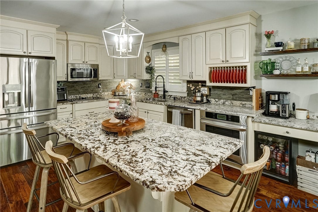1174 Dorset Road, Powhatan, VA 23139 Gourmet kitchen featuring a large island with patterned stone countertop, stainless steel appliances, white cabinetry, and a beverage cooler