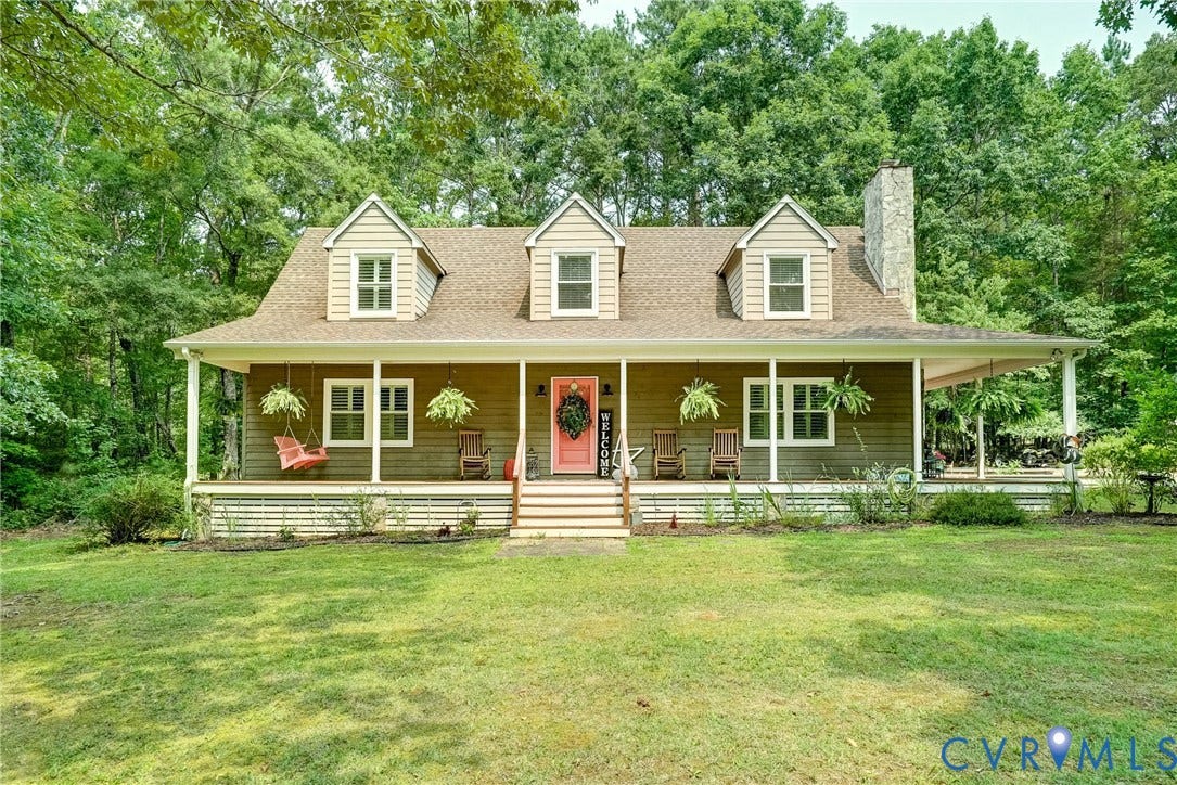 1174 Dorset Road, Powhatan, VA 23139 Cape Cod style residence featuring a full-width covered porch, light wood siding, three dormer windows, a prominent stone chimney, and a vibrant red front door