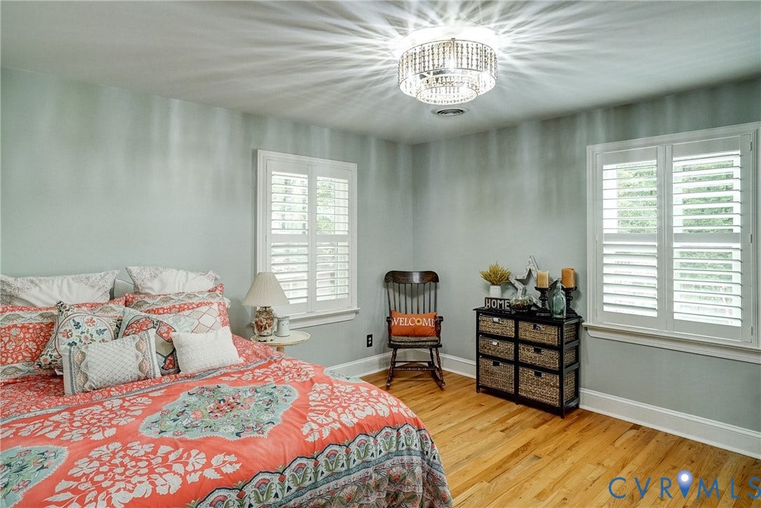 1174 Dorset Road, Powhatan, VA 23139 Bedroom featuring wood-finish flooring, two large windows with white louvered shutters, a ceiling-mounted crystal light fixture, and light-toned wall paint