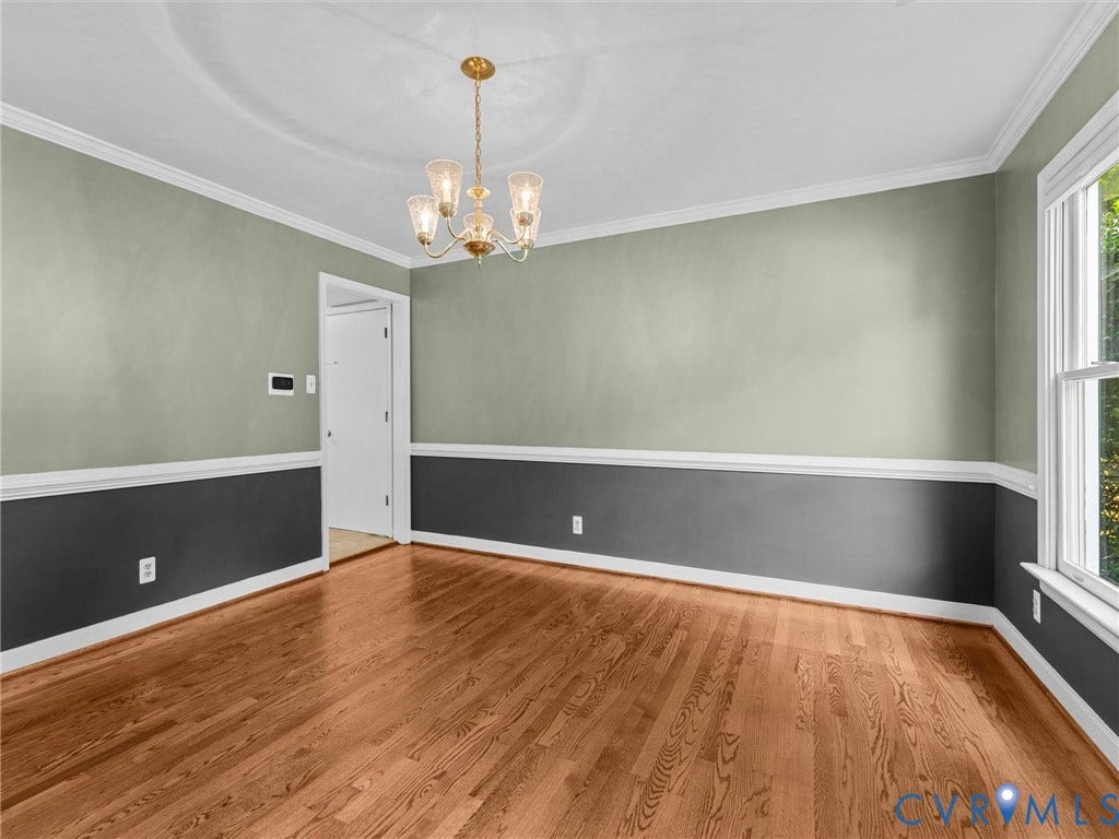 Dining Room featuring hardwood flooring, two-tone wall treatment, crown molding, and a decorative chandelier