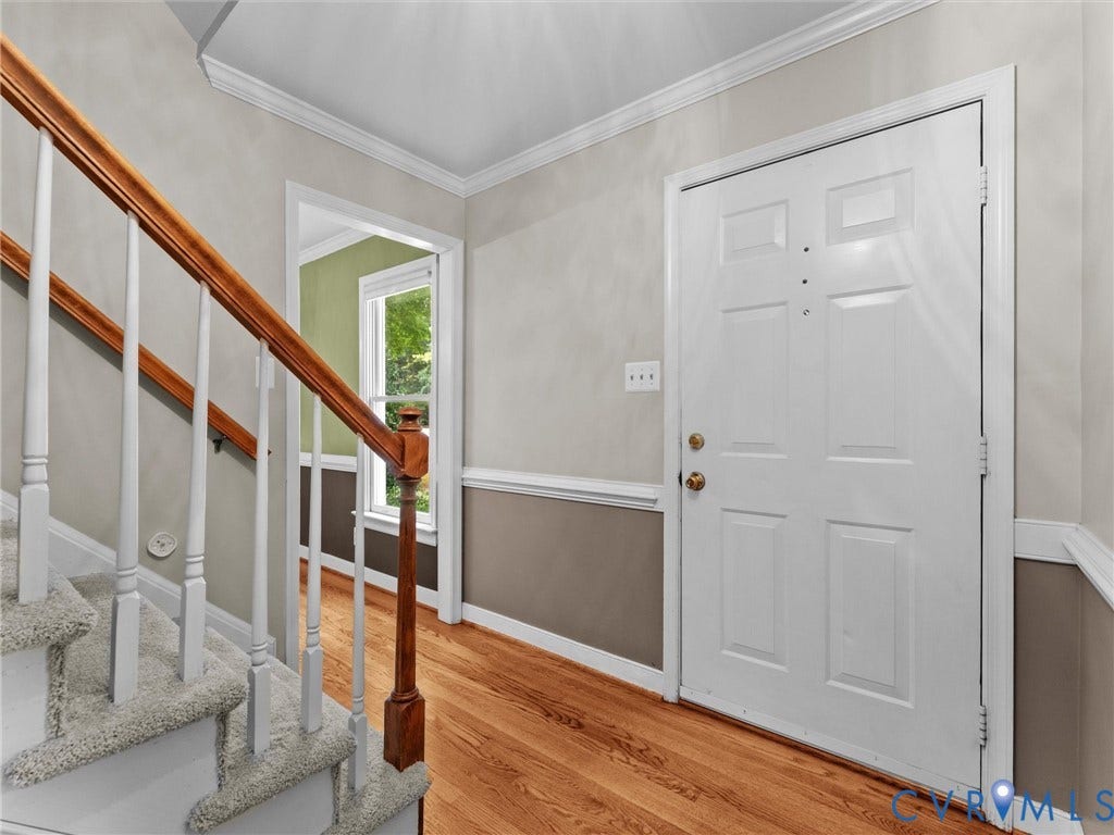 Entry foyer featuring a paneled door, wood-finish flooring, and crown molding