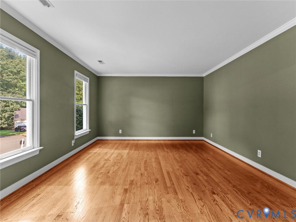 Living Room featuring wood-finish flooring, two large windows, white trim, and crown molding