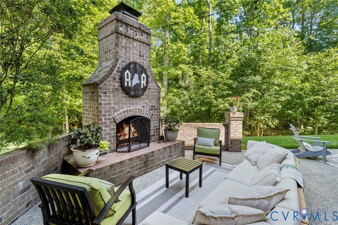 1925 Muswell Court, Hallsley, Midlothian, VA 23112 Outdoor patio featuring a large brick fireplace, a low brick retaining wall, strung overhead lighting, a decorative area rug, and ample space for seating