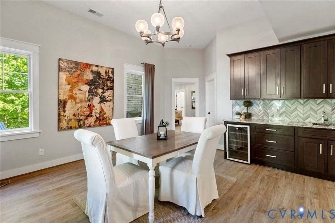 1925 Muswell Court, Hallsley, Midlothian, VA 23112 Dining area featuring wood-finish flooring, vaulted ceilings, and a built-in wet bar with a beverage cooler, dark wood cabinetry, and a chevron tile backsplash